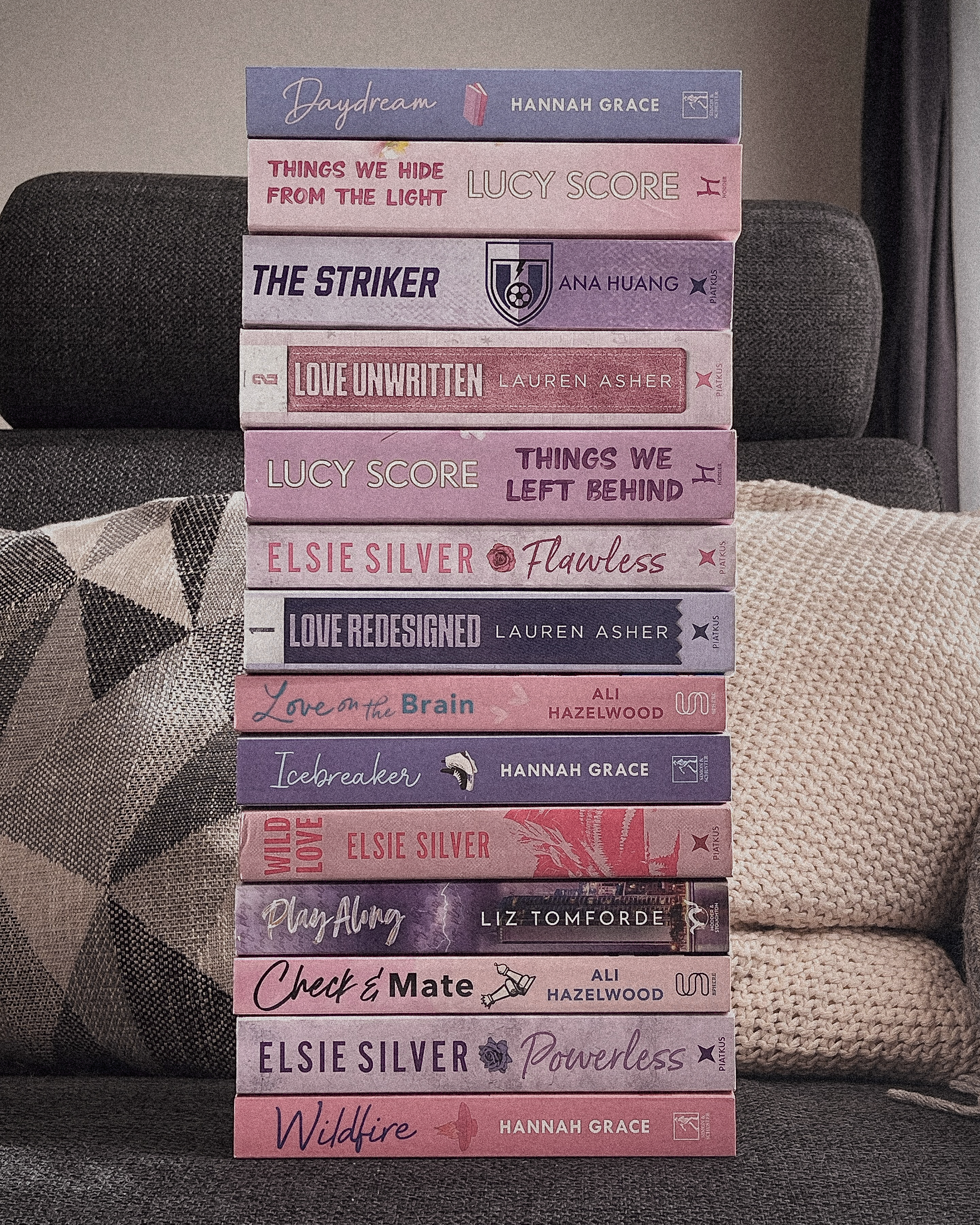 A stack of purple and pink books on a couch