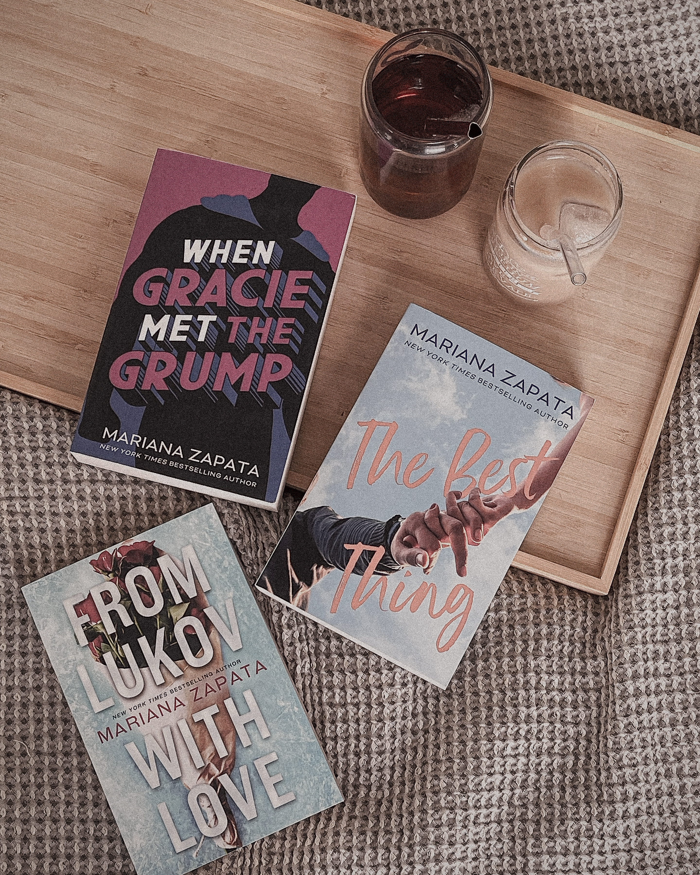Three books, a glass of ice tea and a glass of ice coffee on a wooden tray